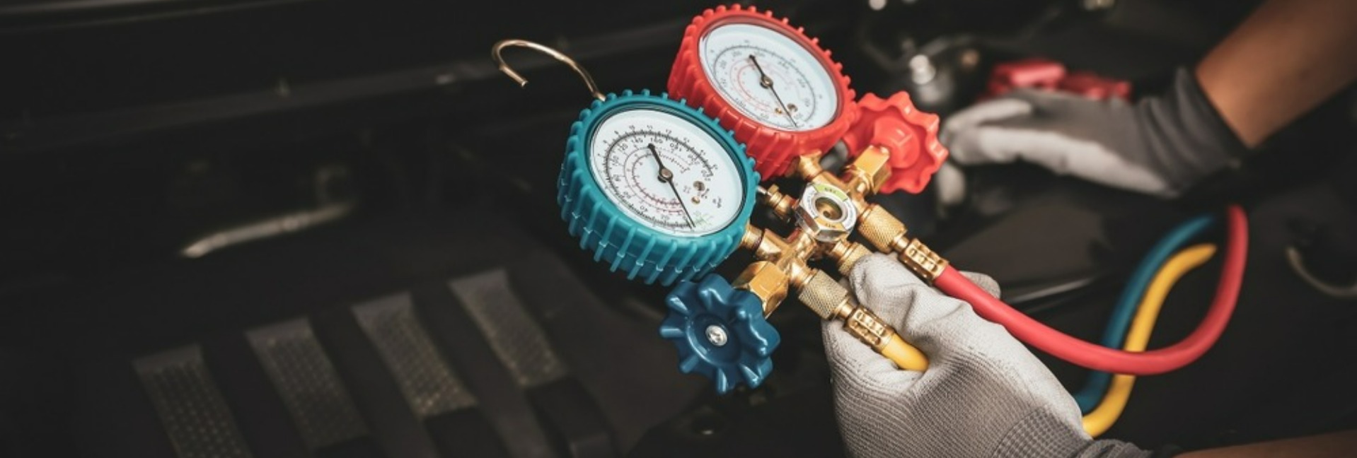 Photo of a car mechanic's hand using a meter to measure vehicle components in a workshop.