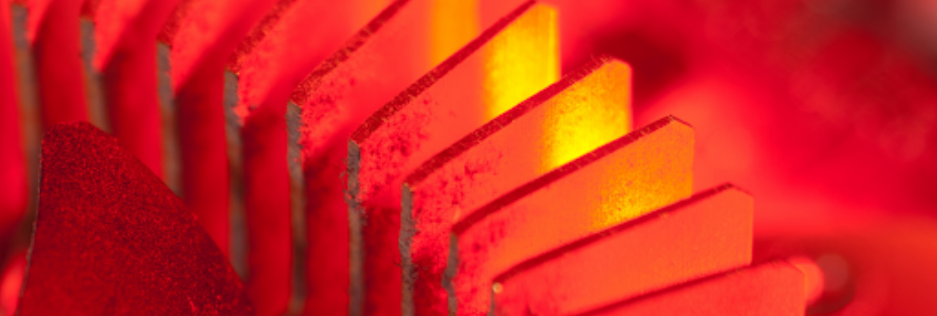 Close-up of red illuminated heat sinks on an electronic device, with a focus on the glowing edges and the textured surface showing signs of thermal wear.