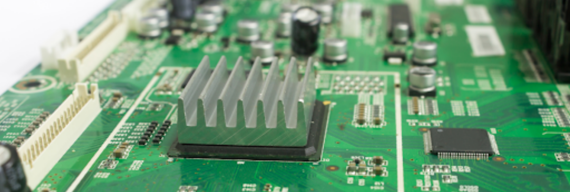 A green circuit board featuring a solitary, unpowered aluminum heat sink amidst various electronic components.